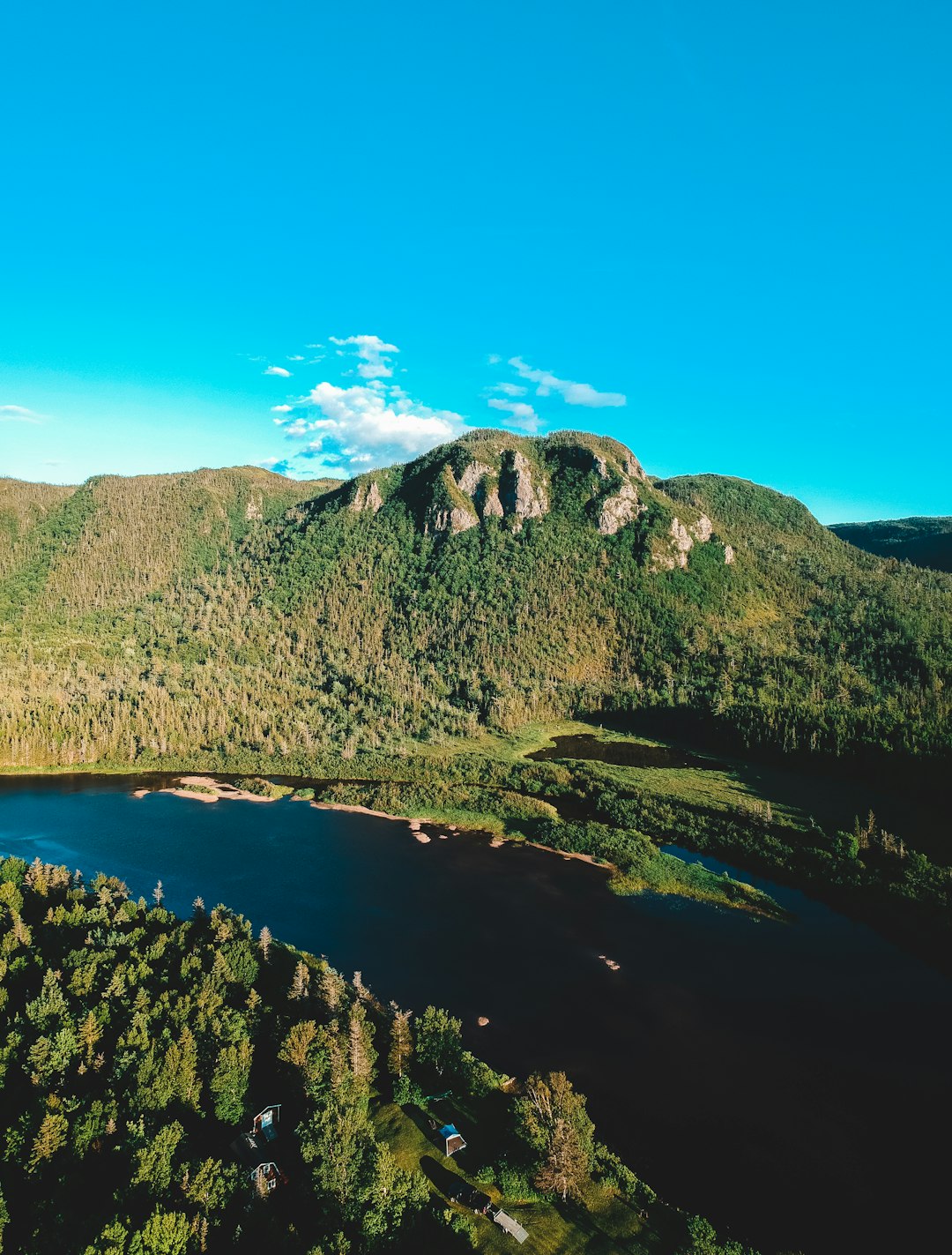 green mountain beside blue lake under blue sky during daytime