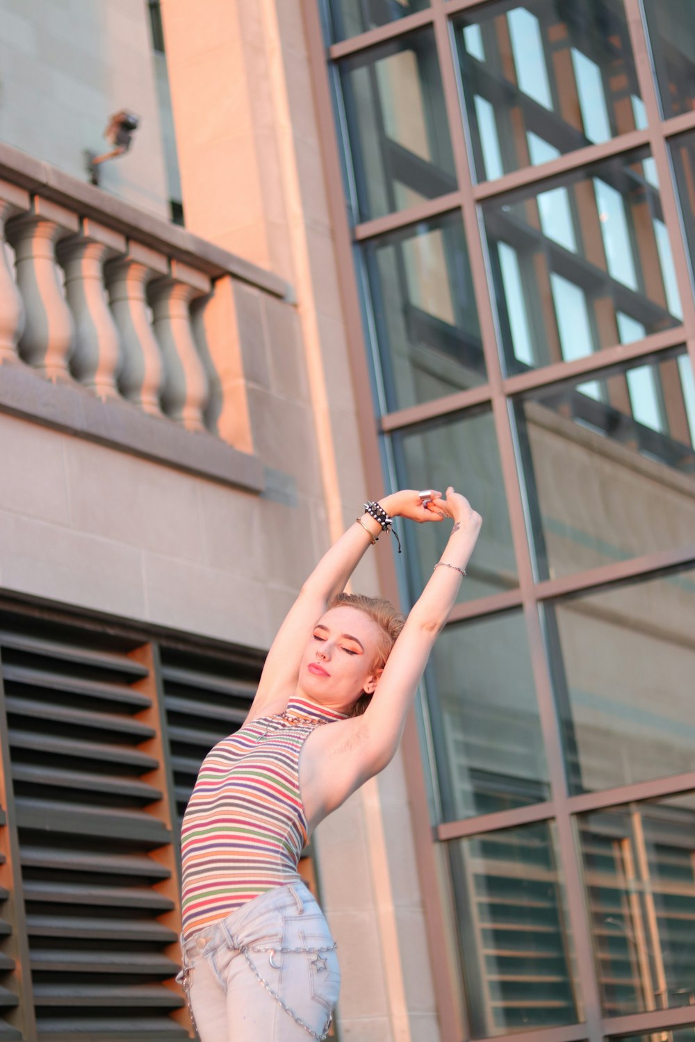 woman in red and white stripe tank top and black and white striped pants raising her