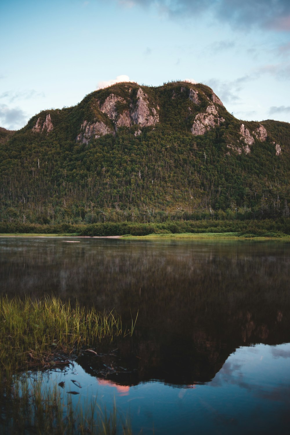 green and brown mountain beside lake during daytime