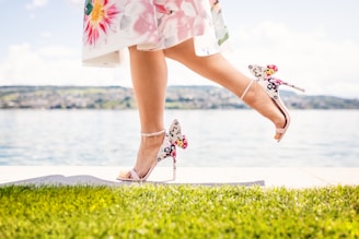 woman in white and pink floral dress standing on green grass field during daytime