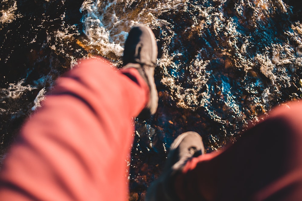 person in pink pants and black shoes standing on water