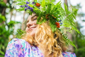 woman in purple and white floral shirt holding green plant
