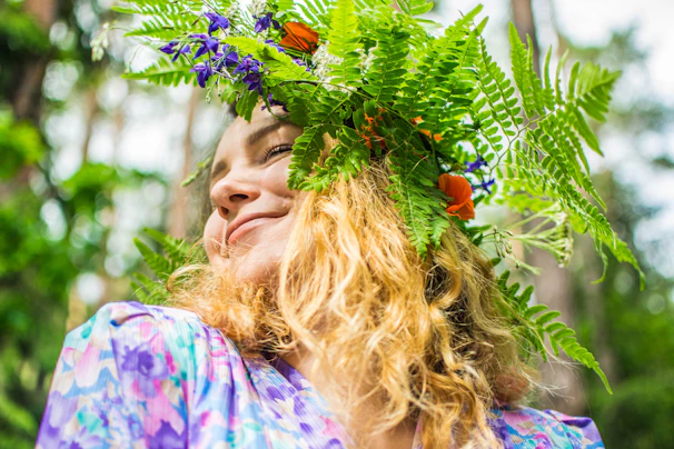 woman in purple and white floral shirt holding green plant