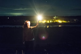 woman in white long sleeve shirt standing on field with sun rays