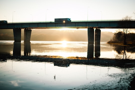 gray concrete bridge over body of water during daytime in Kaunas Lithuania
