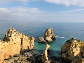 brown rock formation on sea under blue sky during daytime