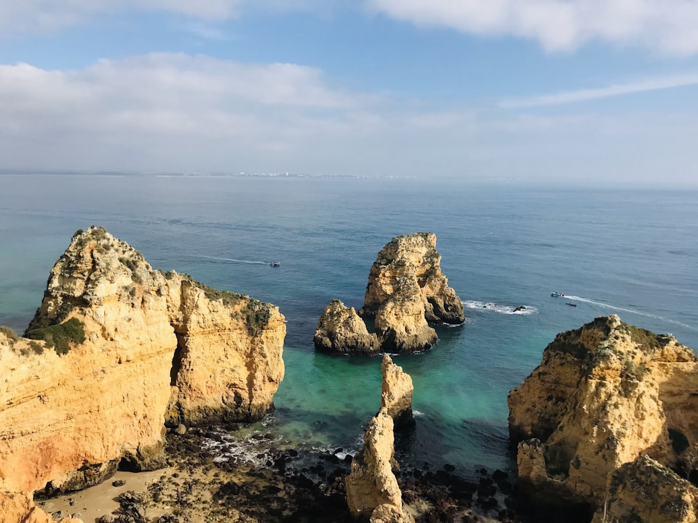 brown rock formation on sea under blue sky during daytime