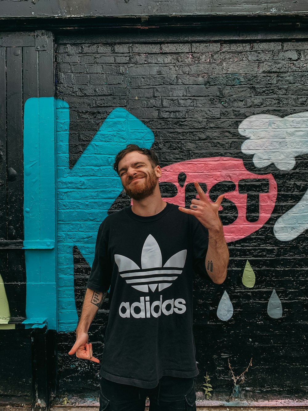 man in black and white crew neck t-shirt standing beside blue wall