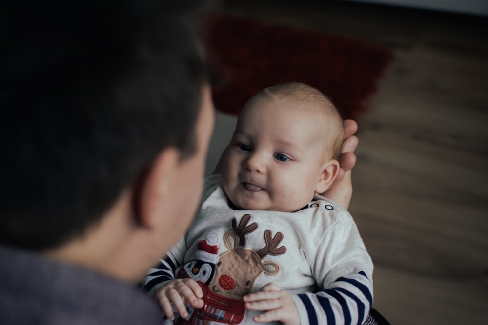 baby in white and black stripe onesie lying on red and white textile