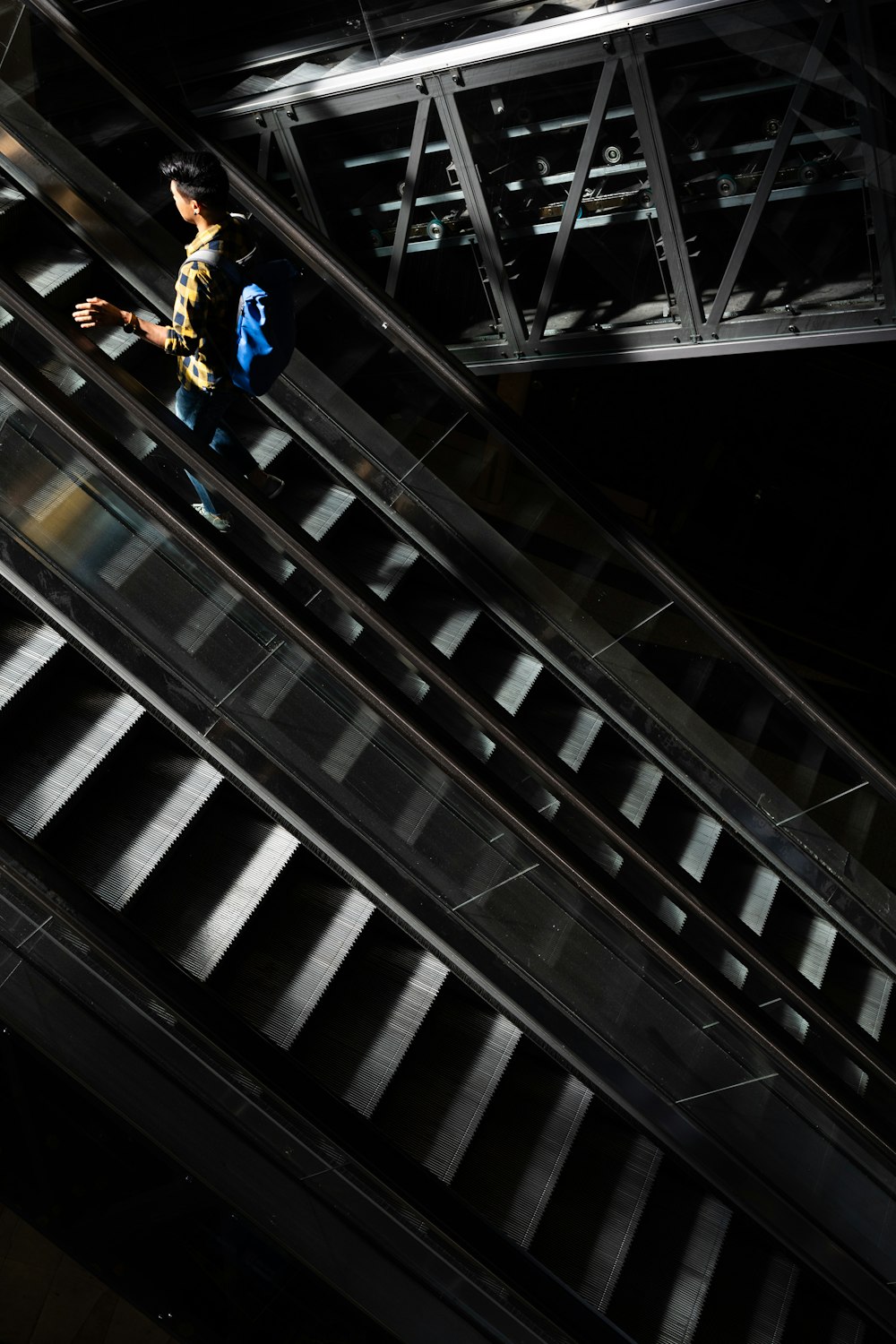 homme en veste jaune et jean bleu debout sur l’escalator