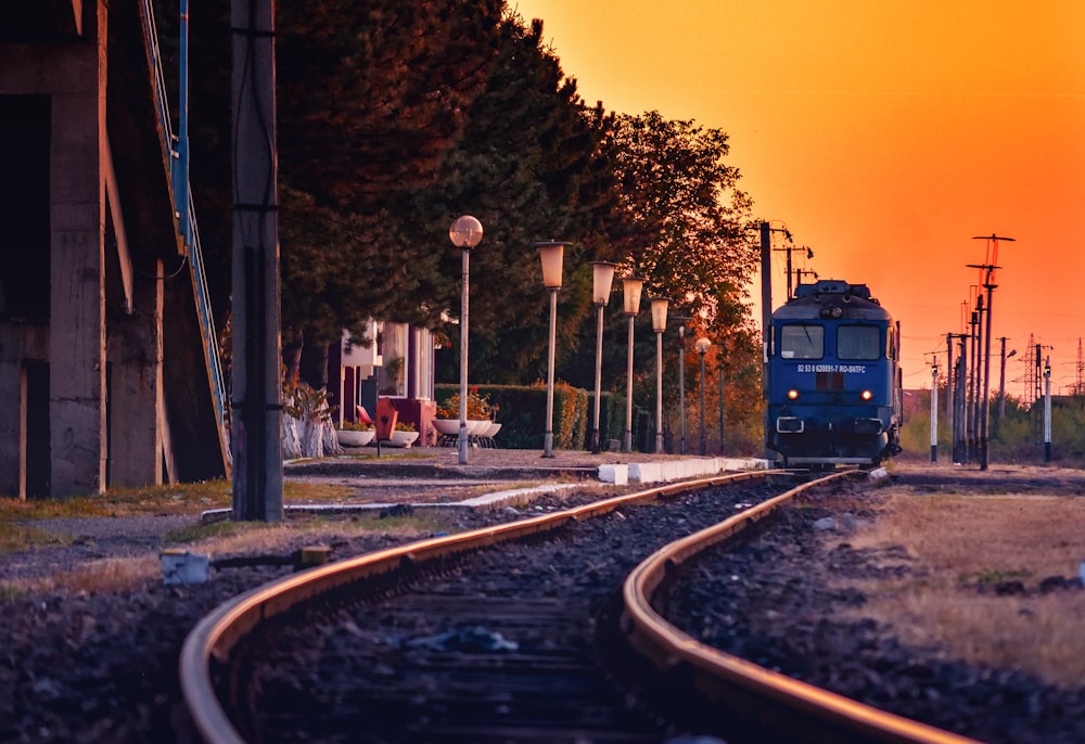 Train bleu sur la voie ferrée au coucher du soleil