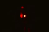 A single red traffic light is illuminated against a dark background, emitting a strong red glow.