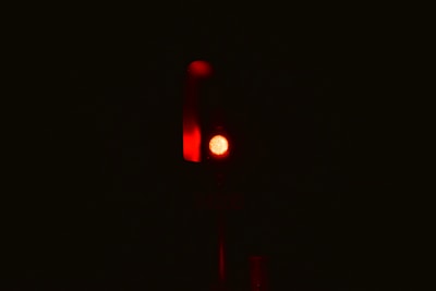 A single red traffic light is illuminated against a dark background, emitting a strong red glow.