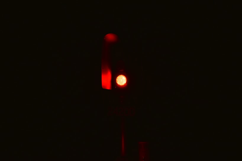 A single red traffic light is illuminated against a dark background, emitting a strong red glow.