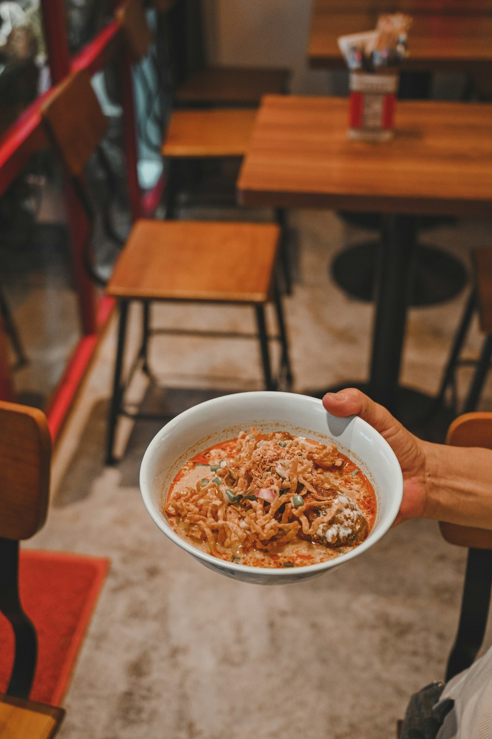 person holding white ceramic bowl with brown food