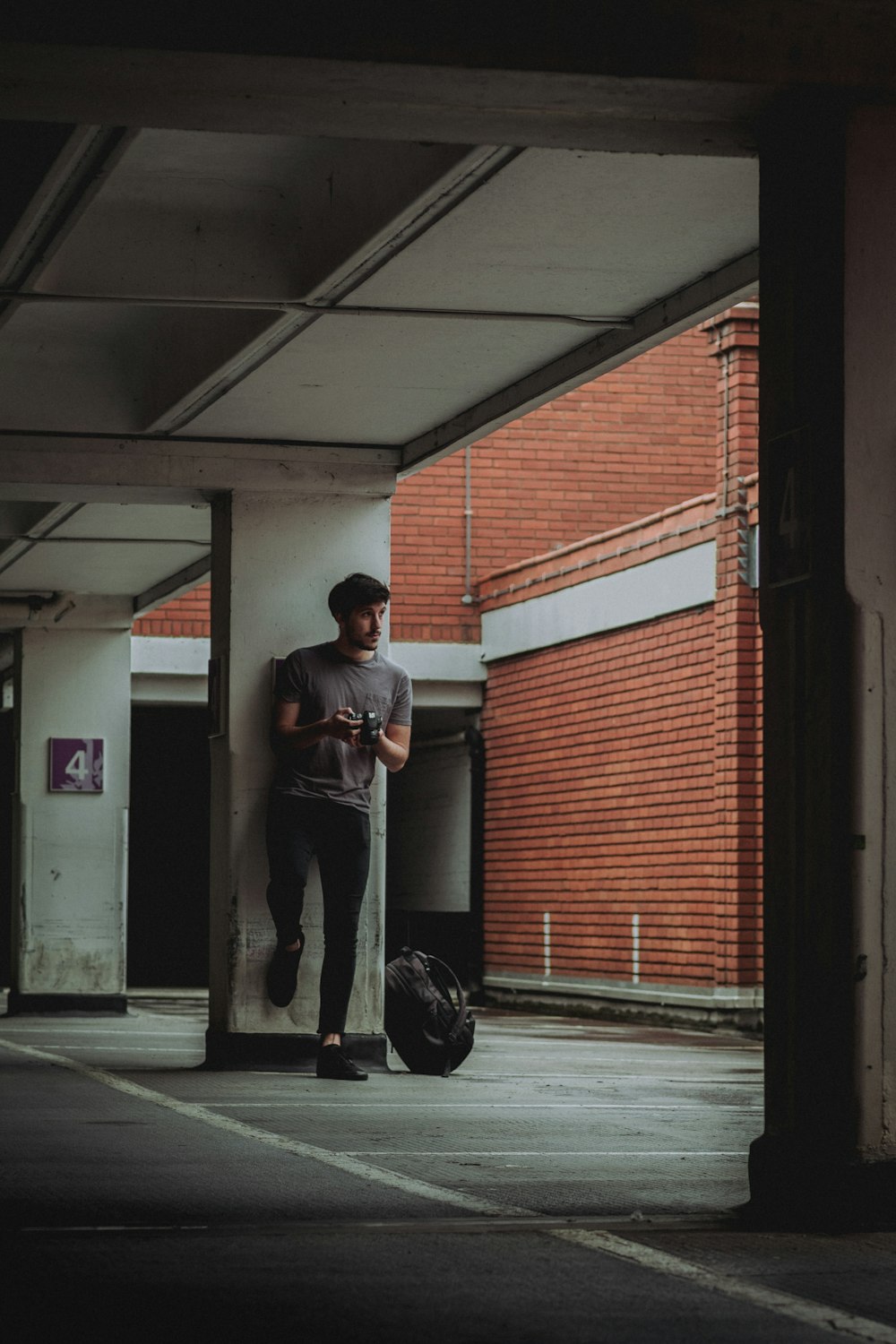 man in black t-shirt and black pants standing near red and white building during daytime