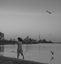 A joyful runner jogging along a coastal trail at sunrise, with a backpack and a city skyline in the distance.
