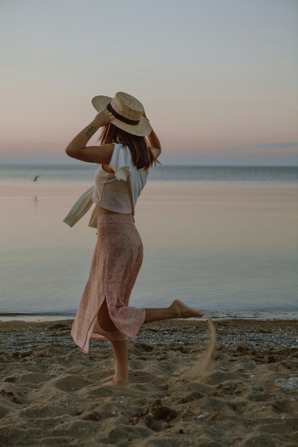 woman in white dress and brown hat standing on seashore during daytime