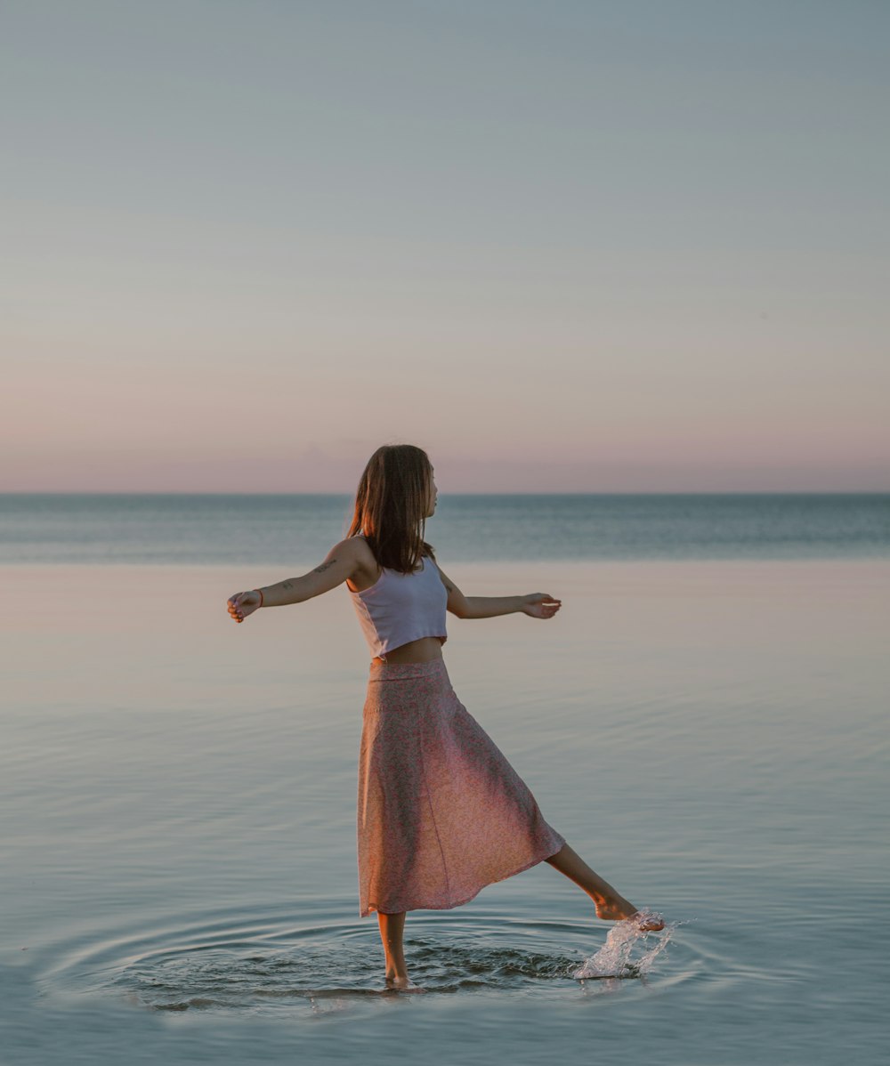 femme en robe rose debout sur l’eau pendant la journée