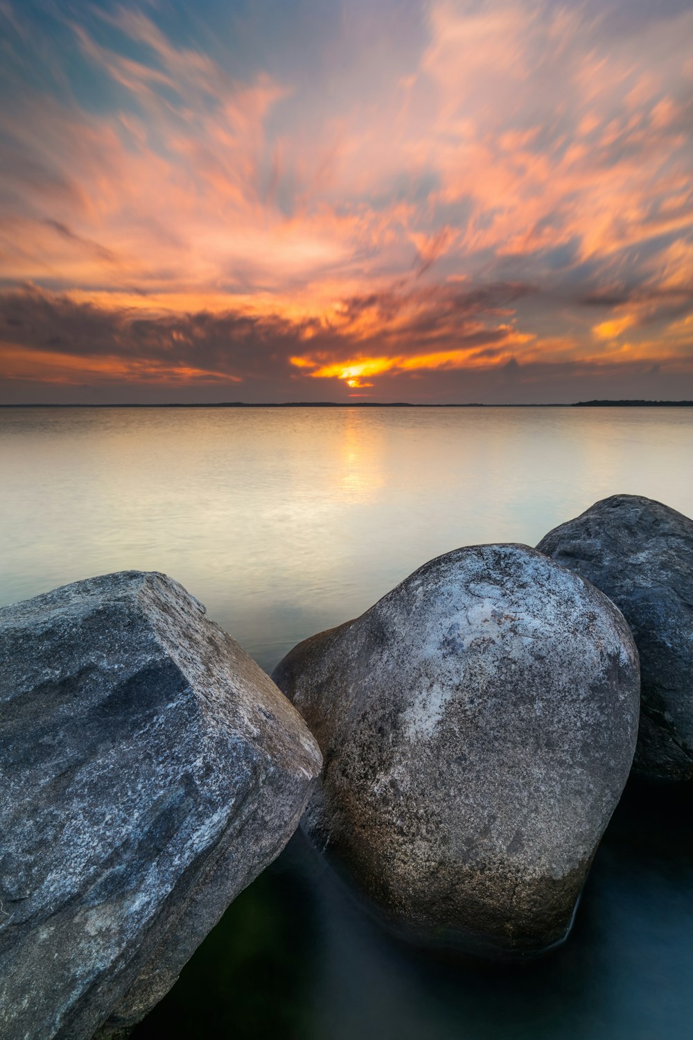 Formation rocheuse grise près d’un plan d’eau au coucher du soleil
