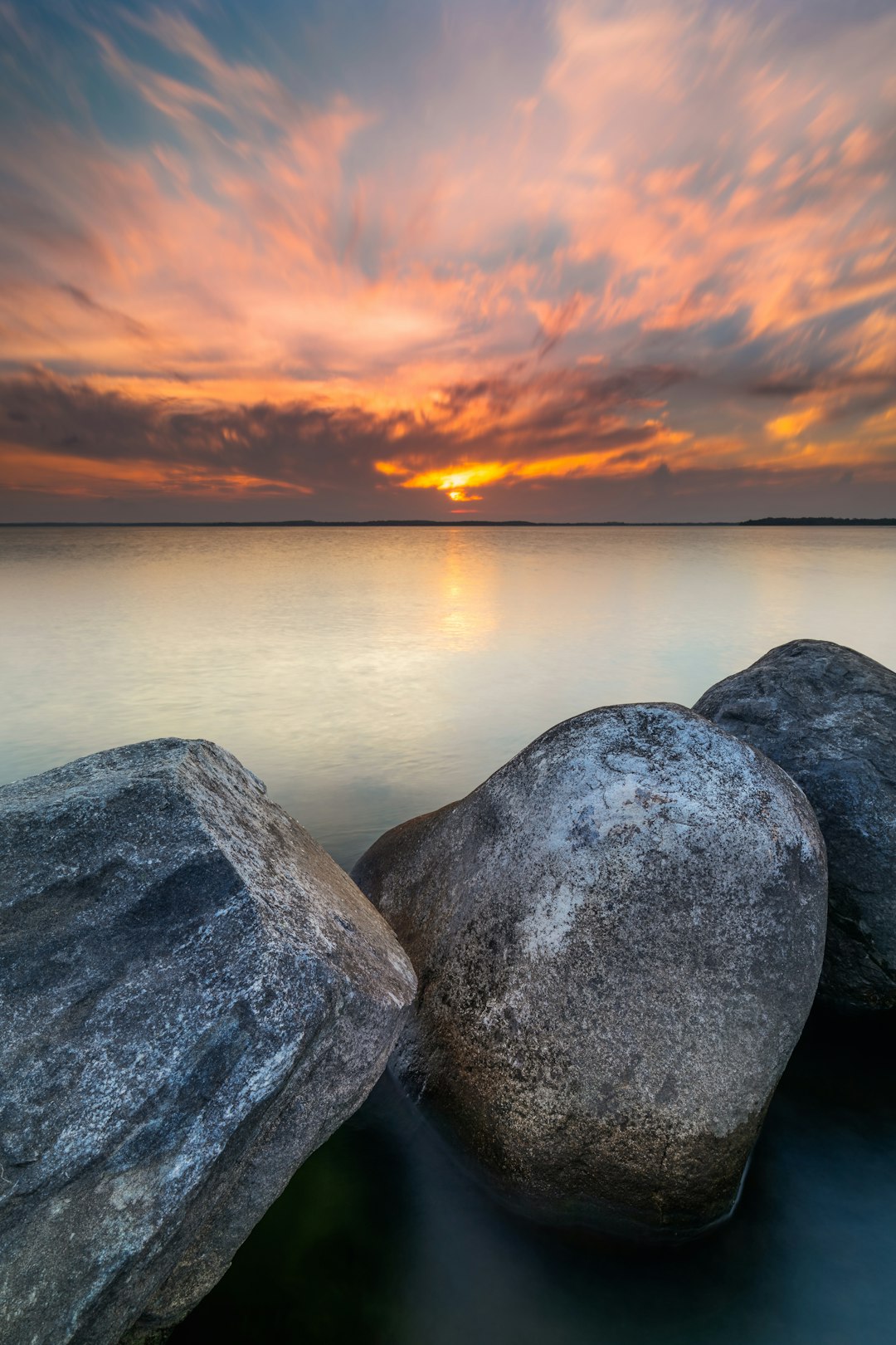 gray rock formation near body of water during sunset