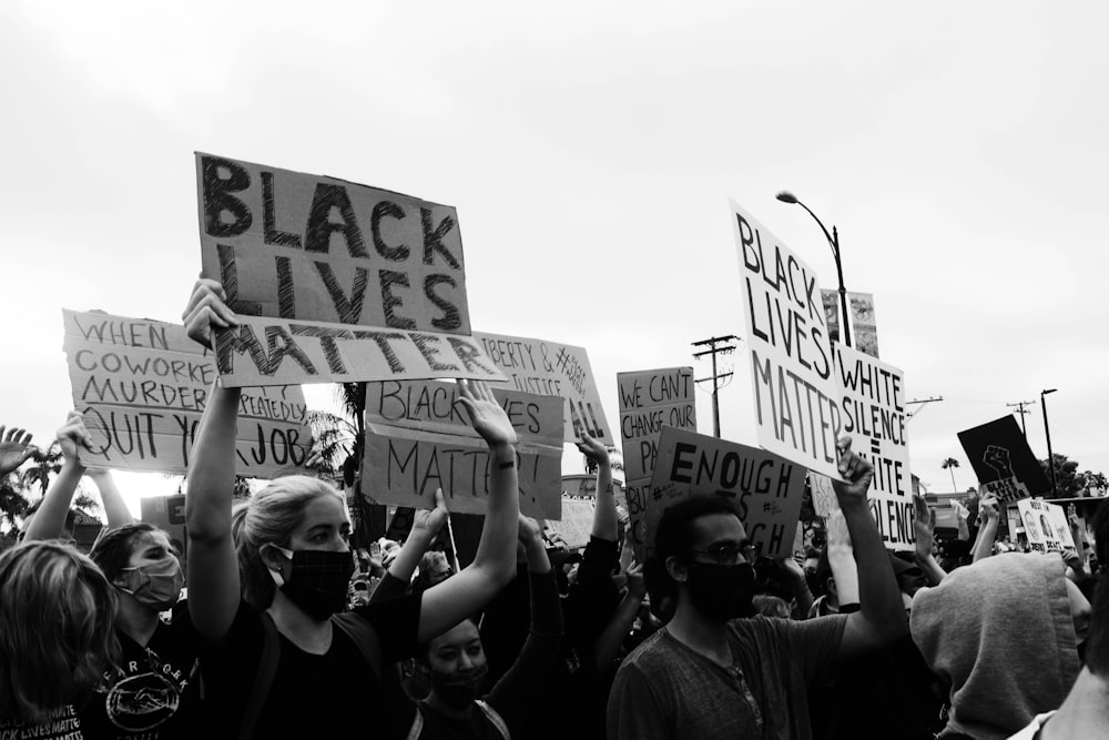 grayscale photo of people holding a signage