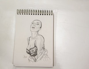 A skilled designer sketching a custom women's dress on a drawing pad.