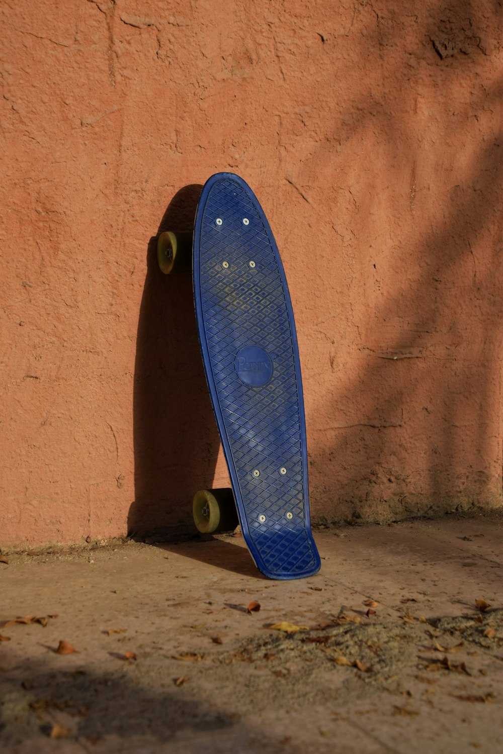 blue and white skateboard leaning on brown wall