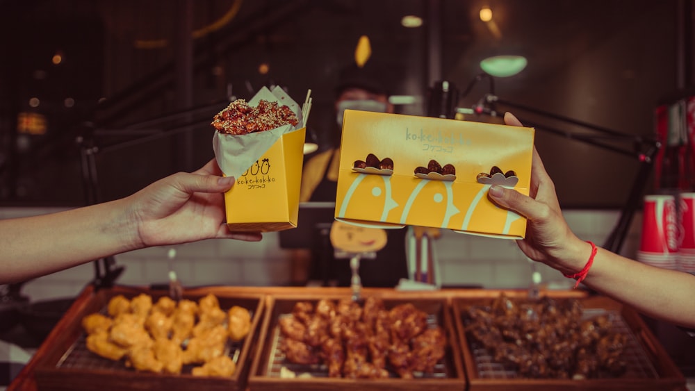 person holding yellow and white box with food