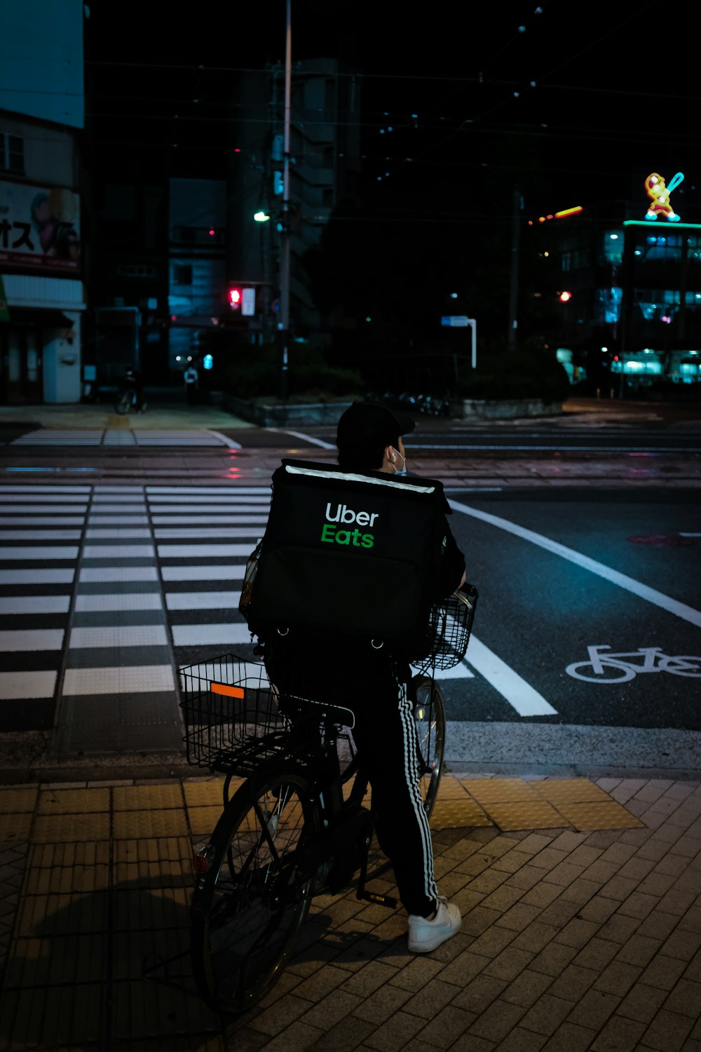 夜間に歩行者専用車線を自転車で走る黒いジャケットの女性