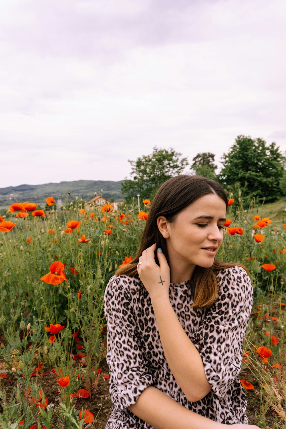 mulher na camisa preta e branca da estampa da estampa da onda, de manga comprida em pé no campo de flores vermelhas durante