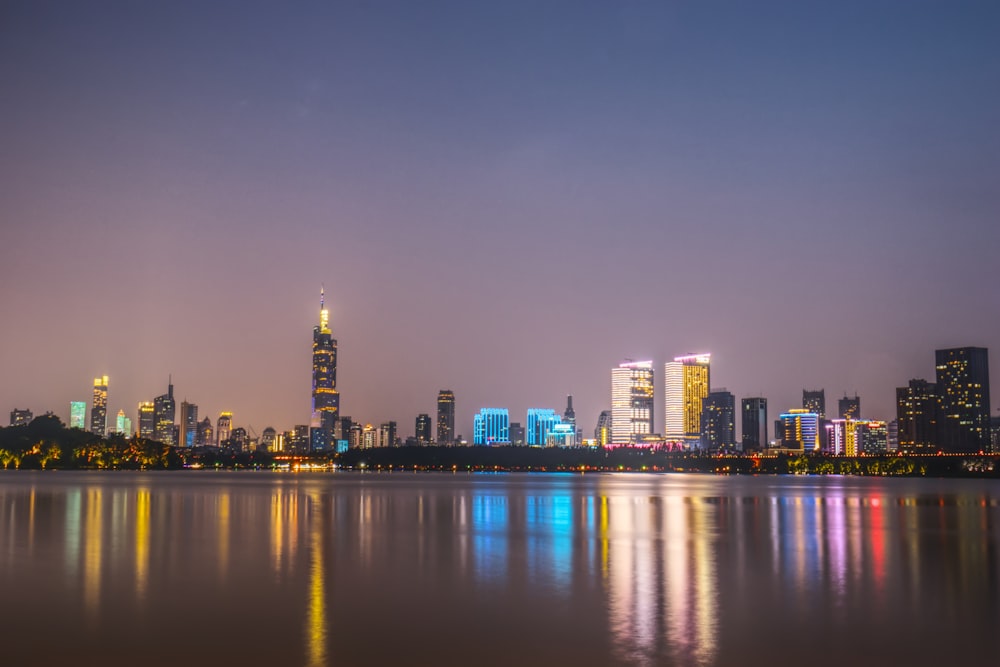 city skyline across body of water during night time