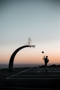 Young athlete training on a basketball court with a sunset background