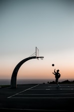 A close-up of a basketball spinning on a player's finger on an outdoor court at sunset.