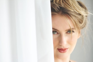 woman in white shirt leaning on white curtain