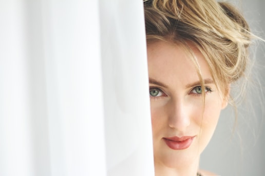 woman in white shirt leaning on white curtain