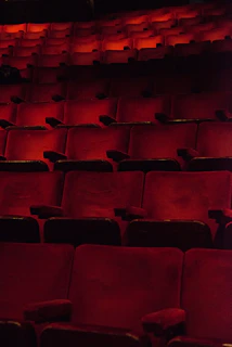 Wide shot of an empty theater seat framed by deep shadows and subtle highlights