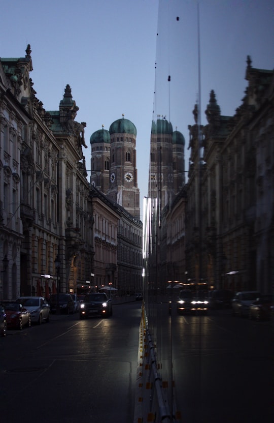 cars parked on side of road in front of brown concrete building during daytime in Frauenkirche, Munich Germany