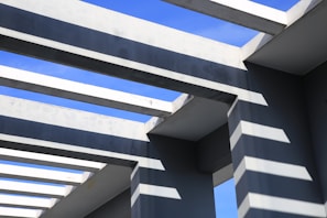 Sunlight streaming through scaffolding beams against a clear blue sky.