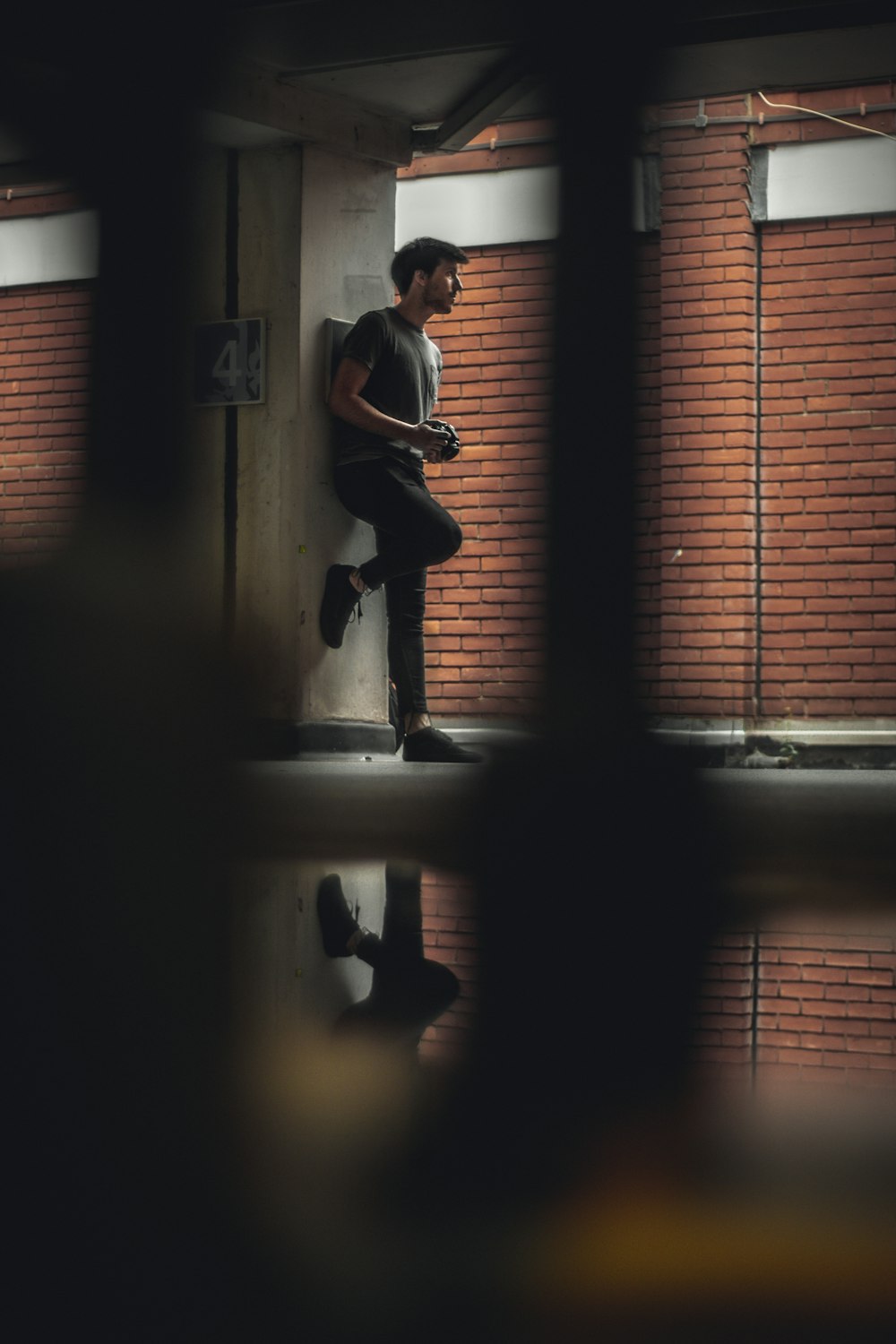 man in white t-shirt and black pants standing beside window