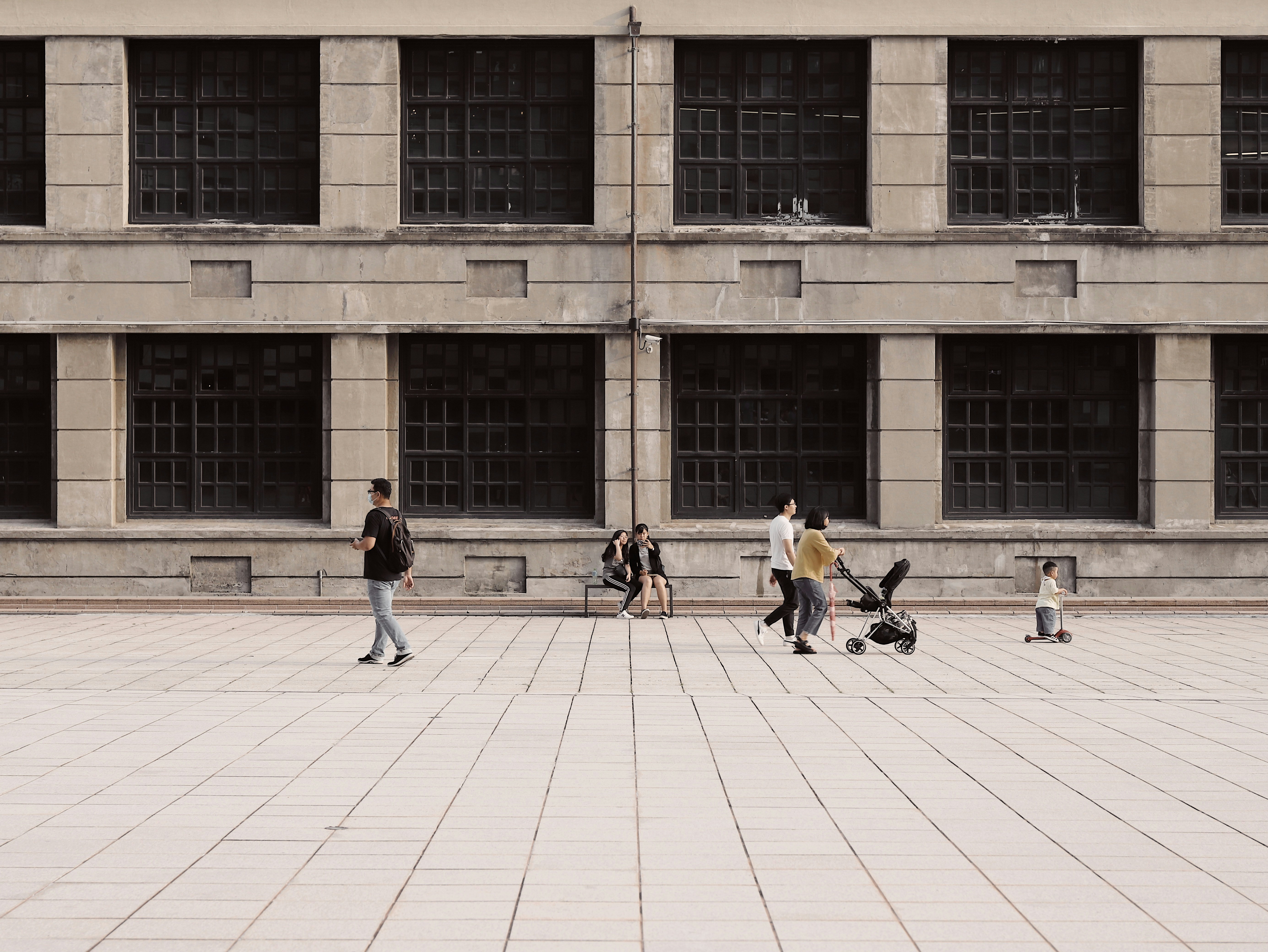 people walking on brown brick floor near brown concrete building during daytime