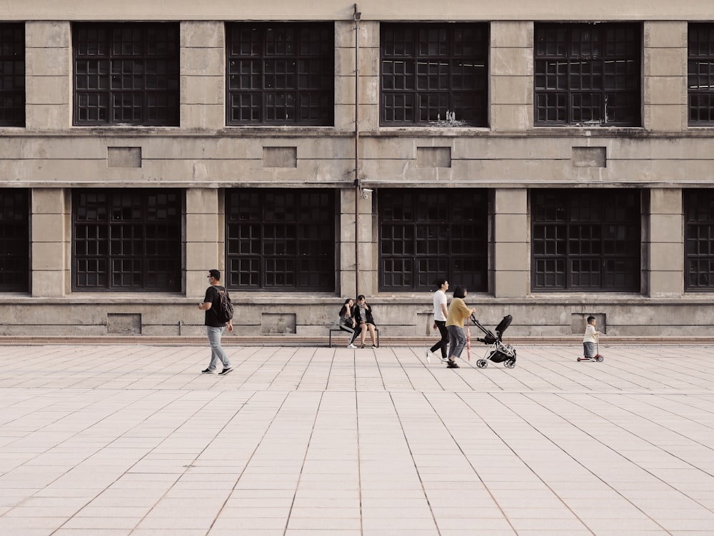 people walking on brown brick floor near brown concrete building during daytime