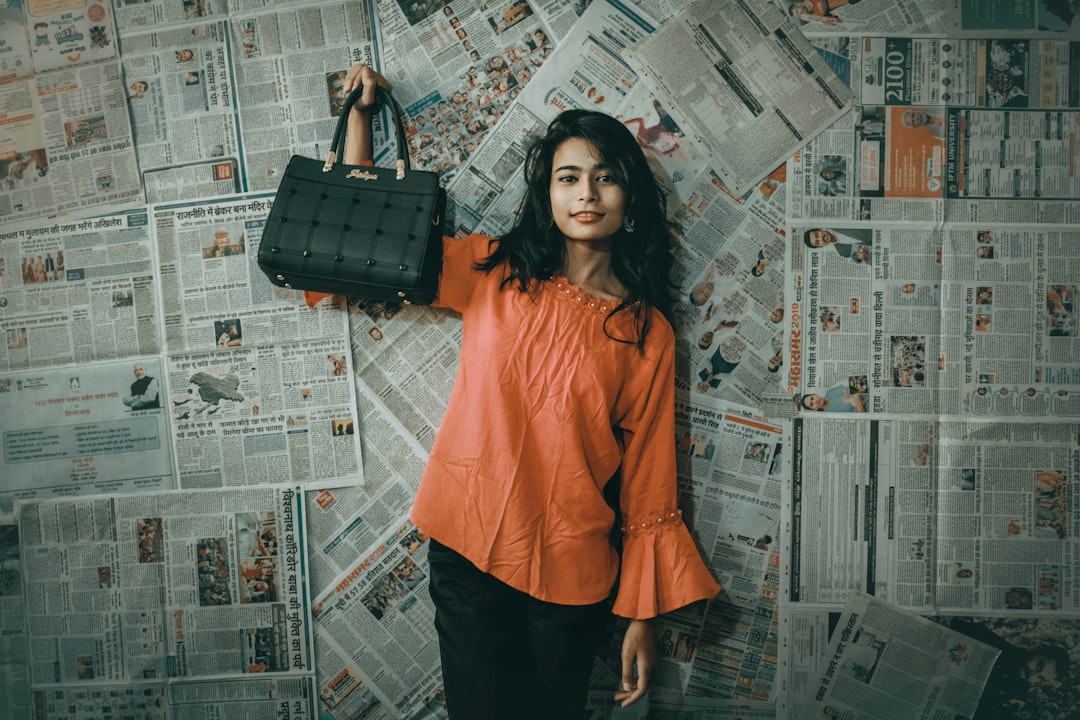 woman in orange long sleeve shirt and black skirt standing beside wall with graffiti