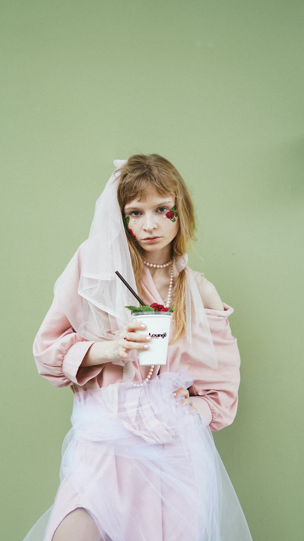 woman in pink robe holding white and green book