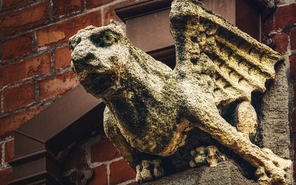 gray concrete statue near brown brick wall