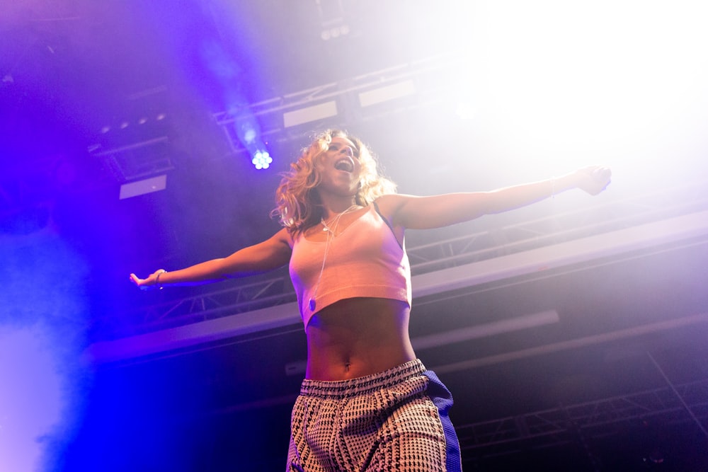 woman in white sports bra and black and white plaid skirt standing on stage