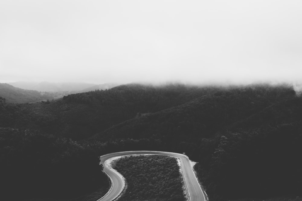 grayscale photo of road between mountains