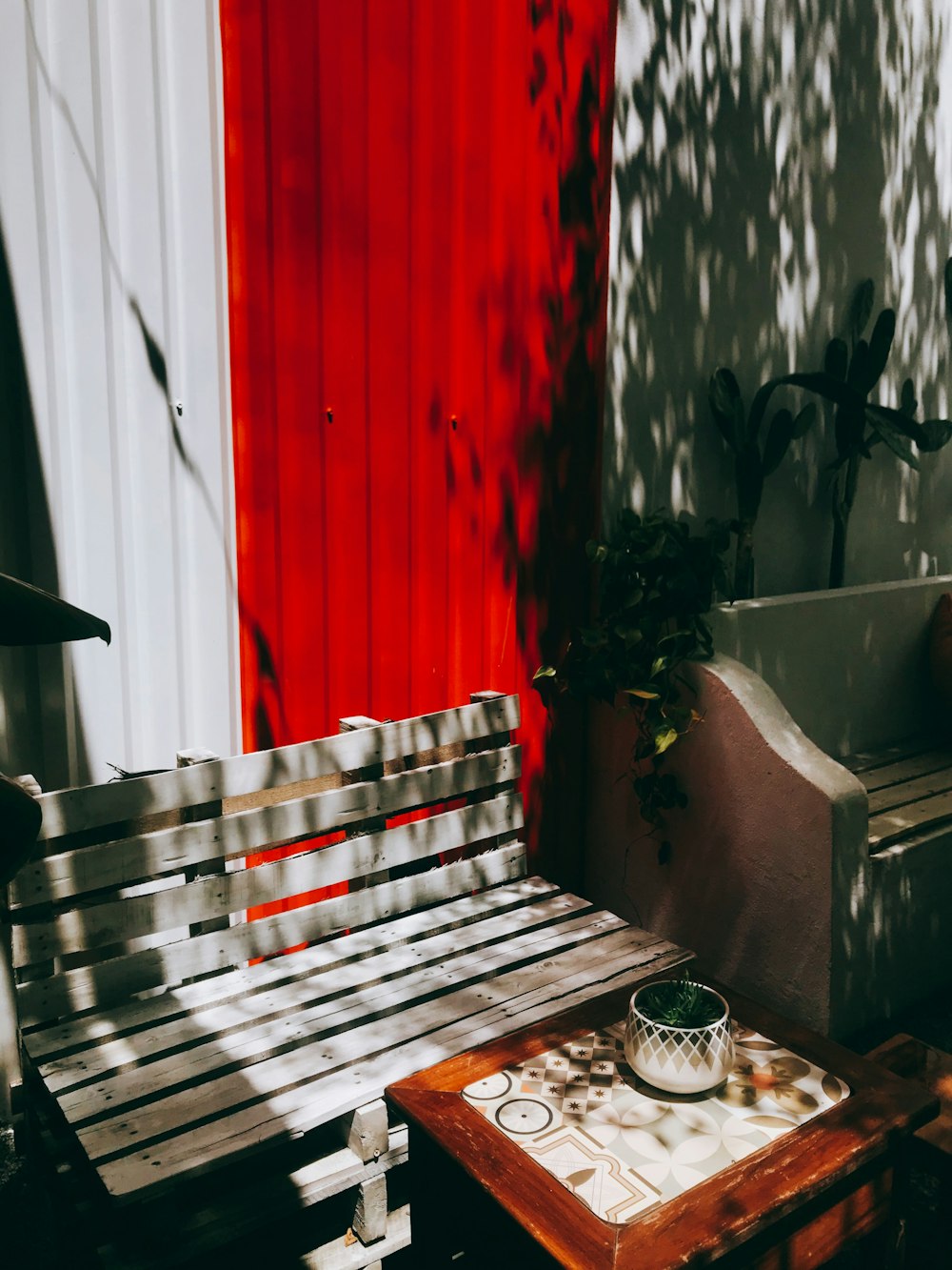 brown wooden bench beside red wall