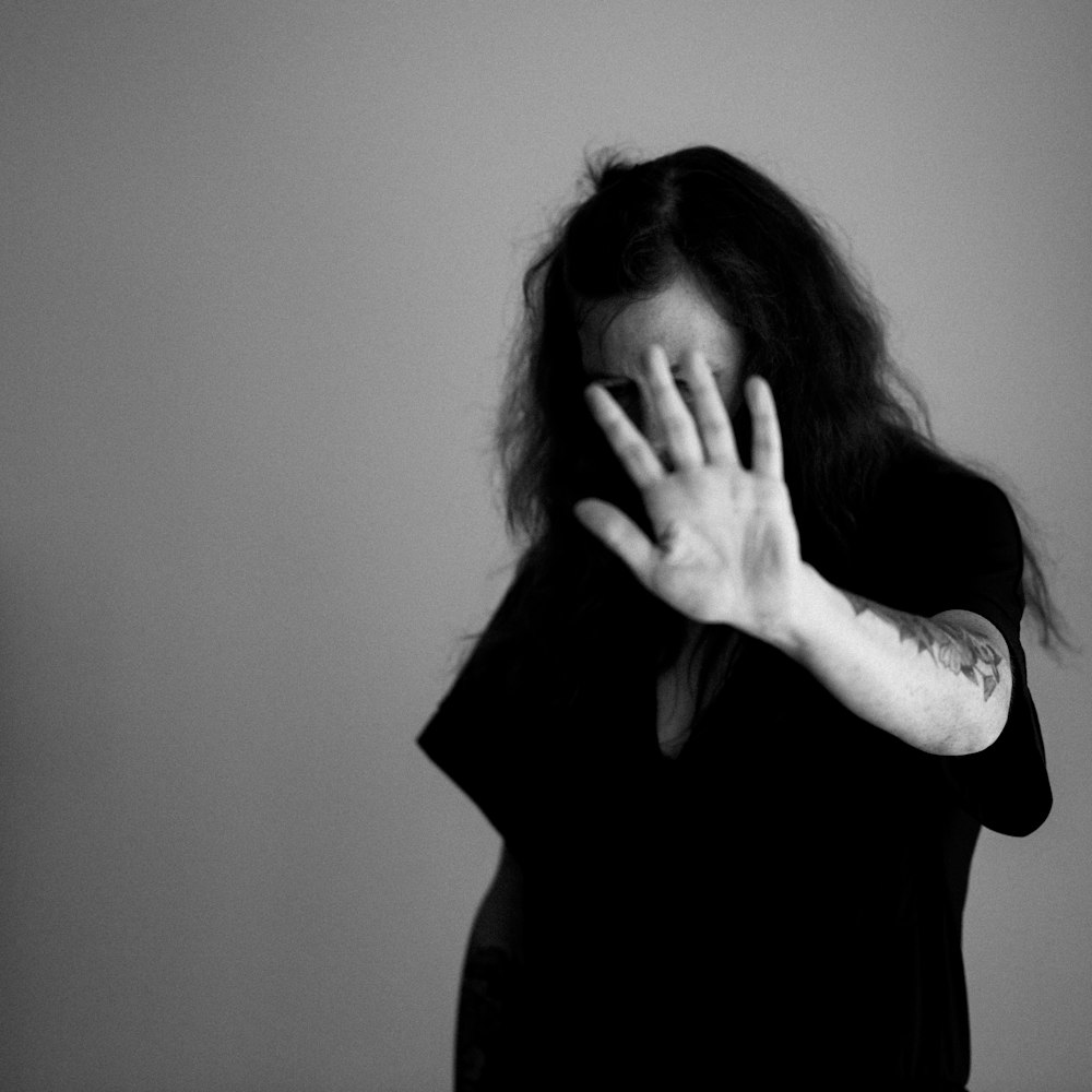 grayscale photo of woman covering her face with her hands