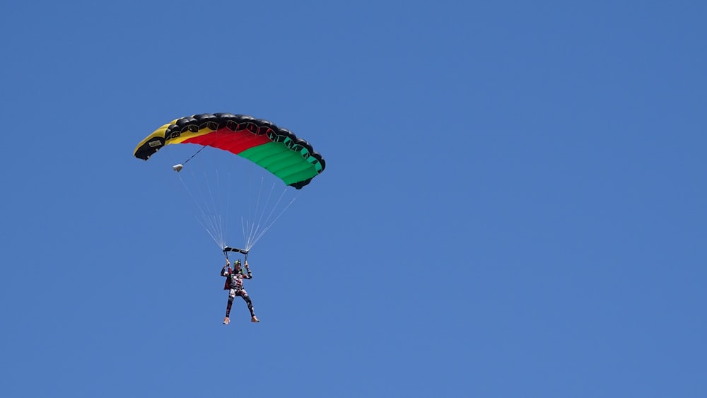 person in black jacket and blue denim jeans riding yellow and red parachute